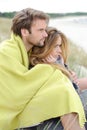 Attractive couple relaxing on the beach in warm clothing on a bright but cool day Royalty Free Stock Photo