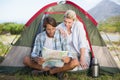 Attractive couple sitting by their tent reading map Royalty Free Stock Photo