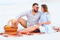 Attractive couple sitting together on the white sand beach, looking each other, happy couple enjoying picnic on the beach and have Royalty Free Stock Photo