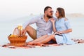 Attractive couple sitting together on the white sand beach, looking each other, happy couple enjoying picnic on the beach and have Royalty Free Stock Photo