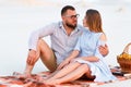 Attractive couple sitting together on the white sand beach, looking each other, happy couple enjoying picnic on the beach and have Royalty Free Stock Photo