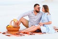 Attractive couple sitting together on the white sand beach, looking each other, happy couple enjoying picnic on the beach and have Royalty Free Stock Photo