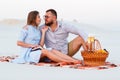 Attractive couple sitting together on the white sand beach, looking each other, happy couple enjoying picnic on the beach and have Royalty Free Stock Photo