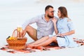 Attractive couple sitting together on the white sand beach, looking each other, happy couple enjoying picnic on the beach and have Royalty Free Stock Photo