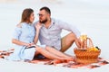 Attractive couple sitting together on the white sand beach, looking each other, happy couple enjoying picnic on the beach and have Royalty Free Stock Photo
