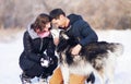 Attractive couple smiling and having fun in winter park with their husky dog Royalty Free Stock Photo