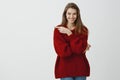Attractive creative girlfriend has interesting idea. Pleased successful romantic woman in trendy loose sweater, pointing