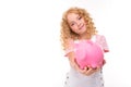 Attractive curly european girl holding a piggy bank in her hands on a light blue wall with copyspace