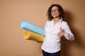 Attractive curly Hispanic woman with beautiful smile in business casual outfit wearing eyeglasses, holding rolls with colored Royalty Free Stock Photo