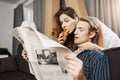 Attractive cute wife standing near husband reading his newspaper and eating croissant while hugging him from back Royalty Free Stock Photo
