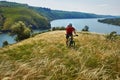 Attractive cyclist riding mountainbike on the meadow above river in summer season in the countryside. Royalty Free Stock Photo