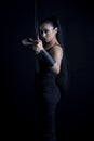 An attractive dark-haired woman dressed in an urban fantasy style outfit and posing against a black backdrop