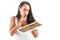 Attractive dark-haired woman is eating a chocolate candy while holding a full candy box. Closed eyes show how tasty the chocolate Royalty Free Stock Photo
