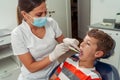 Attractive dentist performs a simple eye examination of the young patient`s mouth. Concept dental care, health care