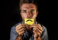 Attractive and depressed man holding paper with smiley sad mouth draw on his lips looking miserable and frustrated suffering depre Royalty Free Stock Photo