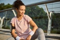 Attractive determined African American female athlete, beautiful sportswoman in pink t-shirt looking away sitting on a squat Royalty Free Stock Photo