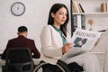 Disabled businesswoman reading business newspaper in office Royalty Free Stock Photo