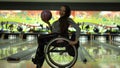 Attractive disabled girl in a wheelchair having fun in the bowling, dancing with a bowling ball