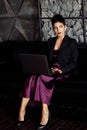 Attractive elegant business woman in fashion dress sit on the sofa, using laptop. Stylish beautiful female boss develop