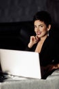 Attractive elegant business woman in fashion dress sit at the sofa, using laptop. Stylish beautiful female boss look at