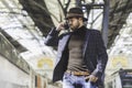 Attractive elegant young hispanic man holding smart phone in his hand and calling while he standing at the railway Royalty Free Stock Photo