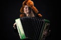 Attractive emotional woman in fur hat playing the accordion