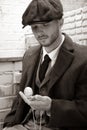 Handsome English gangster sitting in costume looking at pocket watch.