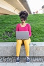 Attractive entrepreneur girl works with her laptop and her tablet sitting in a park in a quiet area without people