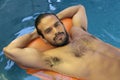 Attractive ethnic man floating in swimming pool