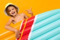 Attractive European blond boy in a summer panama with an inflatable swimming board on a orange background Royalty Free Stock Photo