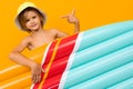 Attractive European blond boy in a summer panama with an inflatable swimming mattress on a orange background Royalty Free Stock Photo