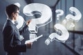 Attractive european businessman with abstract question marks sketch standing in blurry office interior. Solution and brainstorm Royalty Free Stock Photo