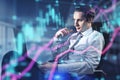Attractive european businessman sitting and looking at laptop computer with glowing forex index chart with grid on blurry office Royalty Free Stock Photo