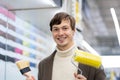 attractive european man holds paint roller and paintbrush in his hands in a hardware store Royalty Free Stock Photo