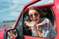 attractive excited girl in sunglasses gesturing and sitting in car