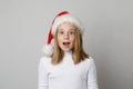 Attractive excited kid girl wearing Santa hat on white background, Christmas portrait