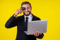 Attractive excited young brunette man isolated over yellow background holding laptop computer and plastic credit card Royalty Free Stock Photo