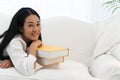 Face smile of young woman lying on white sofa with yellow stack of book looking at camera