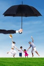 Attractive family jumping at field under umbrella Royalty Free Stock Photo