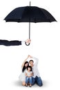 Attractive family sitting under umbrella in studio Royalty Free Stock Photo