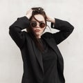 Attractive fashion model pretty young woman in stylish casual youth outfit in trendy sunglasses straightens hairstyle near vintage Royalty Free Stock Photo