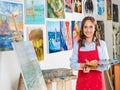 attractive female artist holding painting brush and palette near canvas Royalty Free Stock Photo