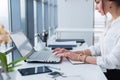 Attractive female assistant working, typing, using portable computer, concentrated, looking at the monitor. Office