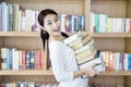 Attractive female bring stack of books in library Royalty Free Stock Photo
