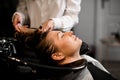 attractive female client relaxed lying on hair washing chair with her eyes closed while hairdresser washes her hair Royalty Free Stock Photo