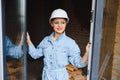 Attractive female construction worker in hardhat. Confident young specialist in checkered blue shirt in jeans standing Royalty Free Stock Photo