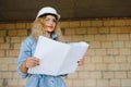 Attractive female construction worker in hardhat. Confident young specialist in checkered blue shirt in jeans standing Royalty Free Stock Photo