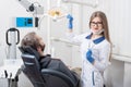 Attractive female dentist getting ready for dental procedure with male patient in modern dental office Royalty Free Stock Photo