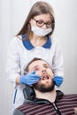 Attractive female dentist getting ready for dental procedure with male patient in modern dental office Royalty Free Stock Photo