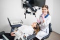 Attractive female dentist with happy woman patient during treatment with microscope in modern dental office Royalty Free Stock Photo